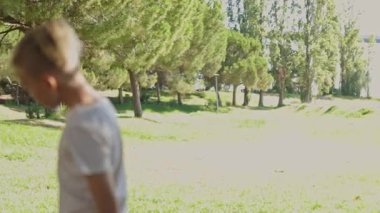 Anne ve çocuklar etkileşime giriyor ve manzaralı bir parkta eğleniyorlar, açık havayı kucaklıyorlar ve yemyeşil ortamda kaynaşıyorlar.