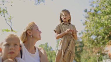 Neşeli aile, çocuklar güneşli bir park ortamını keşfederken ve oynarken dışarıda kaliteli vakit geçirmeyi seviyor. Mutlu anları ve bağlantıları yakalıyorlar.