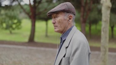 Huzurlu bir parkta rahatlatıcı bir yürüyüş sırasında müziğin tadını çıkaran kıdemli bir adam.