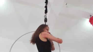 Hava jimnastiği. Havada sallanan bir çemberin içinde dönen genç bir kadın gösteri yapıyor. Orta çekim