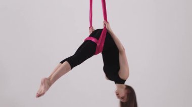 Genç bir kadın hava jimnastiği sırasında kumaş dengesi kurar. Orta çekim