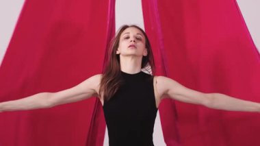 Beyaz stüdyoda pembe bezle dans eden zayıf bir kadın. Orta çekim