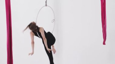 Hava yogası. Tavanın altında asılı duran bir halkayla egzersiz yapan genç bir kadın. Orta çekim