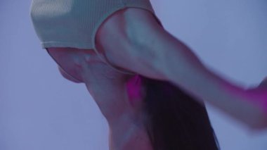 Hava yogası - genç Asyalı jimnastikçi tavanın altında baş aşağı asılı duran bir çemberde gösteri yapıyor - neon ışıklı. Orta çekim