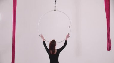 Genç bayan jimnastikçi tavanın altındaki çembere atlıyor. Orta çekim