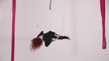 Genç bayan jimnastikçi tavanın altındaki çemberin üstüne çıkıyor. Orta çekim