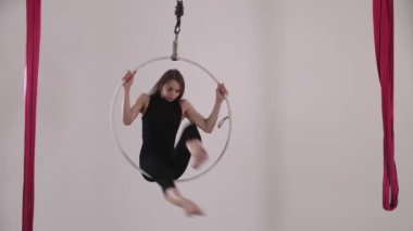 Tavanın altında asılı duran çemberin üzerinde dönen genç ve zayıf bir kadın. Orta çekim