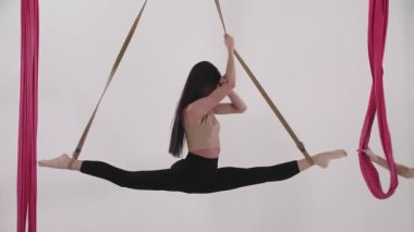 Hava yogası. Genç bir kadın koçun gözetiminde bacaklarını açıyor. Dönüyor. Orta çekim