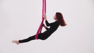 Hava yogası. Kumaşın üzerinde asılı duran ve gösteri yapan bir kadın. Orta çekim