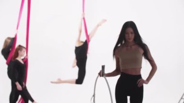 Hava yogası. Eğitime hazırlanan üç genç kadın. Koçları ileri doğru yürür ve kameraya bakar. Orta çekim