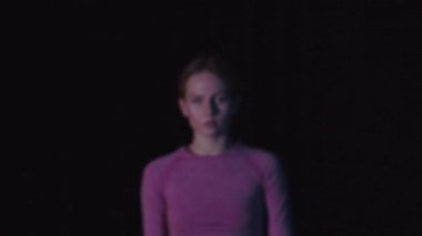 Siyah stüdyoda pembe elbiseli güzel bir kadın kameraya bakıyor. Portre