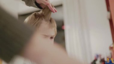 Üzgün çocuk, anne babası tarafından saçını kestiriyor.