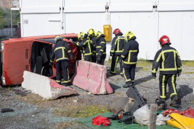 İtfaiyeciler, bir trafik kazasından sonra devrilmiş bir arabadan bir kişiyi çıkarmak için birlikte çalışıyorlar. Ekip çalışması ve kurtarma becerileri gösteriyorlar.