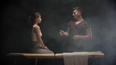 Fizyoterapist masadaki hastaya tedaviyi açıklıyor.