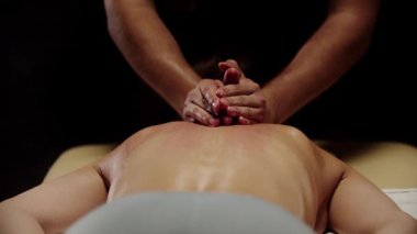 Profesyonel masör erkek müşteriye sırt masajı yapıyor.