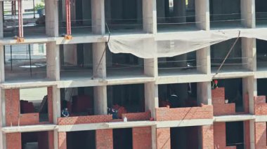 İnşaat işçileri yeni bir konut inşaatı için dış tuğla duvarlar inşa ediyorlar.