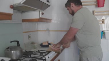 Evcil mutfakta tavuk bacağı kesen adam.