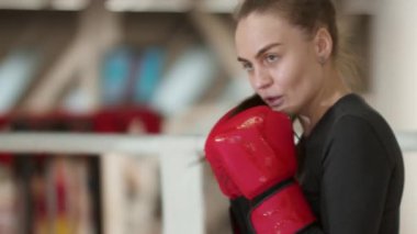 Uzun saçlı çekici genç bir kadın kameraya doğru boks yapıyor. Orta çekim