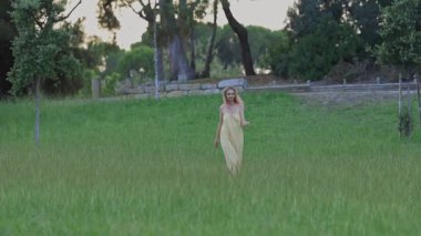 Genç bir kadın altın saatinde tarlada yürüyor