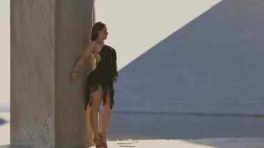 Siyah elbiseli bir kadın duvardan kaçıyor. Sahne gergin ve belirsiz.