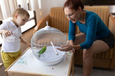 Anne ve oğul evcil hayvanlarıyla kafeslerinde etkileşime girerek, aile ve evcil hayvan kaynaşmasını canlandırıyorlar.