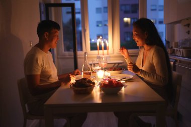 Evlerinde mum ışığında romantik akşam yemeği yiyen Asyalı çift.