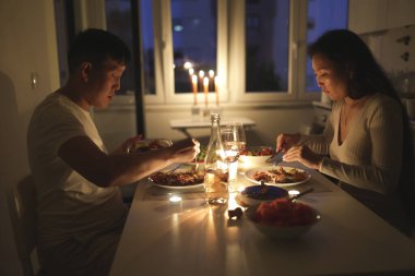 Genç Asyalı çift mum ışığında yemek yiyor.