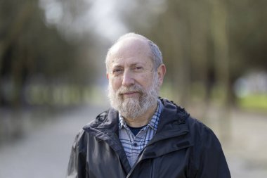 Huzurlu bir park ortamında huzur içinde emekliliğin tadını çıkaran kıdemli bir adam.