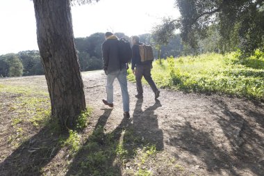 Sırt çantalı iki yürüyüşçü güneşli bir günde ormanda yürüyorlar.