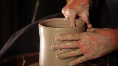 Yaşlı bir kadın kilden bir tencerenin sınırını şekillendiriyor. Orta çekim