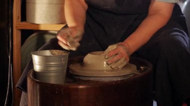 Yaşlı bir kadın bir atölyede ıslak kille çalışıyor - kilde teneffüs yapıyor. Orta çekim