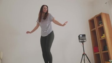 Günlük dansçı oturma odasında koreografi çalışıyor, projektörle kendini kaydediyor.