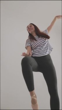 Neşeli ve özgürce dans eden enerjik kadın, beyaz arka planda soyutlanmış.