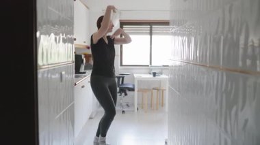 Mutfakta tek başına dans eden mutlu bir kadın.