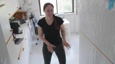 Enerjik bir kadın evde antrenman yapıyor, mutfakta özgürce dans ediyor.