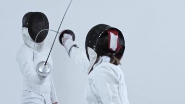 Beyaz stüdyoda iki eskrimci arasında eskrim eğitimi. Orta çekim