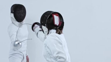 Beyaz stüdyoda eskrim eğitimi alıyorum. İki genç eskrimci arasında. Orta çekim