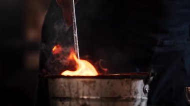 Metal işçisi sıcak metali bir kova suda soğutuyor.