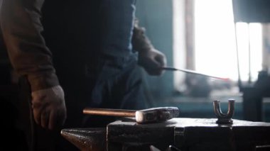 Demirci atölyede örs üzerinde parlayan metali çekiçliyor