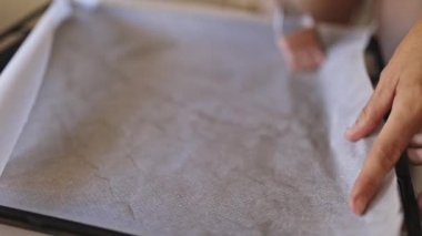 Fırıncı pişirme tezgahında kağıt yağlıyor, pişirmeye hazırlanıyor.