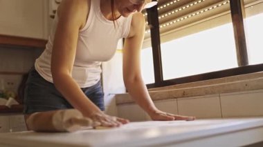 Fırıncı mutfak masasında turta pişirmek için un yayıyor ve hamur yoğuruyor.