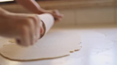 Kadın fırıncı beyaz masada hamur hazırlıyor.