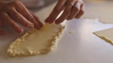 Pasta şefi beyaz bir masada turta kabuğunu süslüyor.