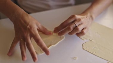 Dişi fırıncı hamuru beyaz yüzeyde kalp şeklinde katlar.