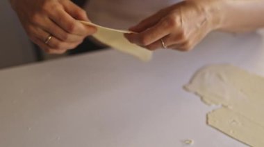 Hamur işi şefi, kalp şeklinde kurabiyeler yapmak için hamuru beyaz masaya ikiye katlar.