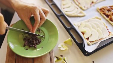 Pasta şefi elmalı turta için tabağa siyah çikolata parçaları ekliyor.