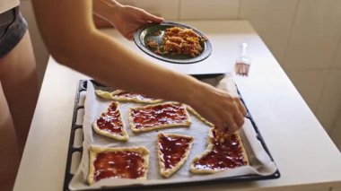 Parlak bir mutfakta ton balığı ve çilekli börek hazırlayan bir kadın.