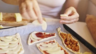 Kadın elmaları dilimliyor ve onları domates soslu ve karamelli soğanlı küçük hamur işleriyle düzenliyor.