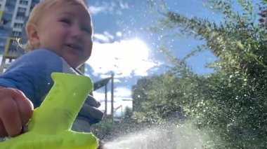 Mutlu çocuk arka bahçede su tabancasıyla oynuyor.