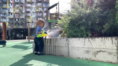 Mutlu çocuk su tabancasıyla oynar, güneşli bir günde su sıkar.